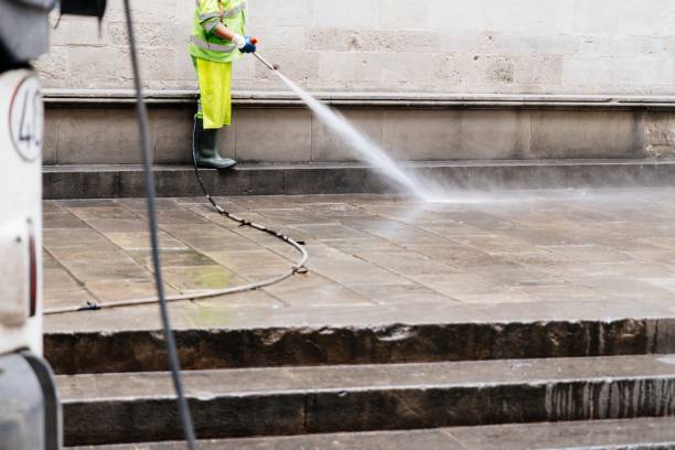 City cleaning worker cleaning street with water high pressure washer